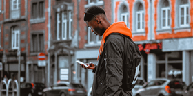 Young black man looking at phone in street thumbnail.png