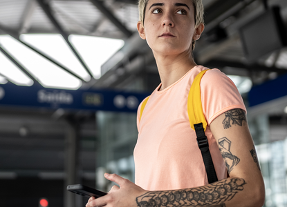 non binary person with tattoos in train station.png