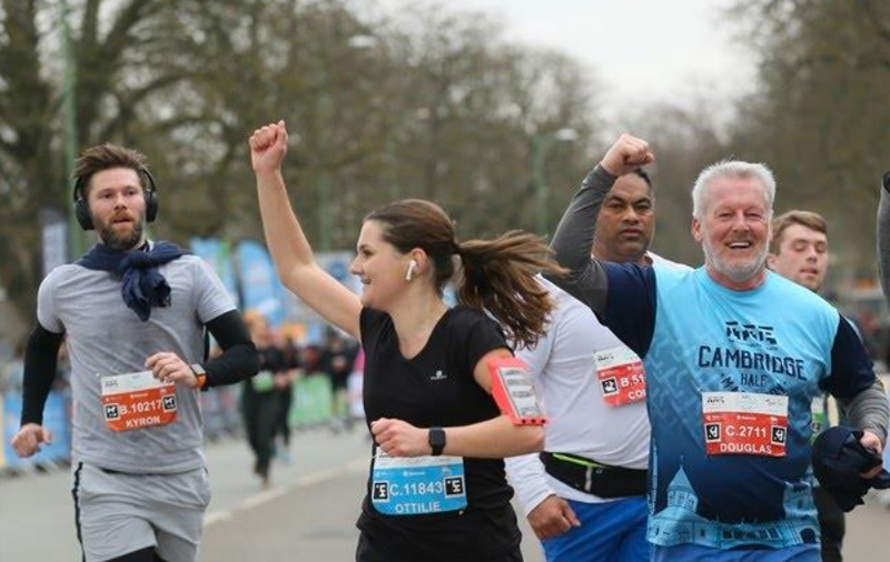 Shout fundraiser Ottilie punches the air as she finishes the Cambridge Half Marathon